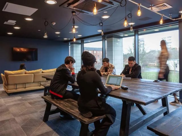 Students study at a table with laptops living room at True Glasgow in Glasgow Student Accommodation