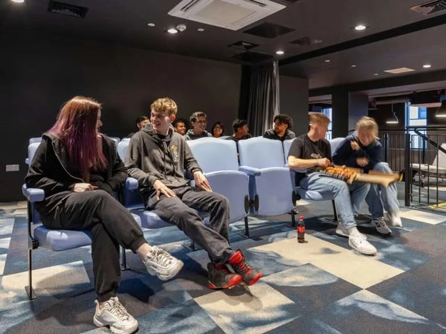 Students sitting in blue seats watching a screen cinema room at True Swansea in Swansea Student Accommodation