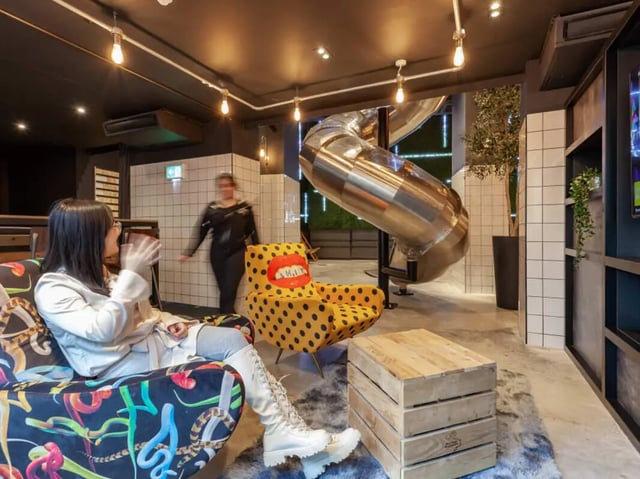 Woman sitting in lounge area with tube slide living room at True Birmingham in Birmingham Student Accommodation