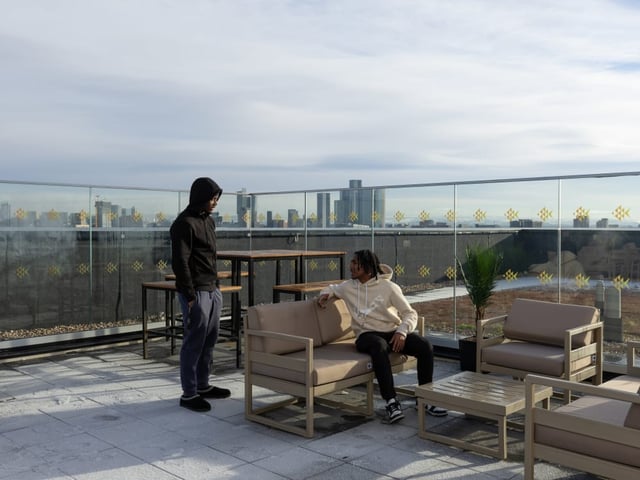 Rooftop lounge area with two people and city view exterior at True Manchester-Salford in Salford Student Accommodation