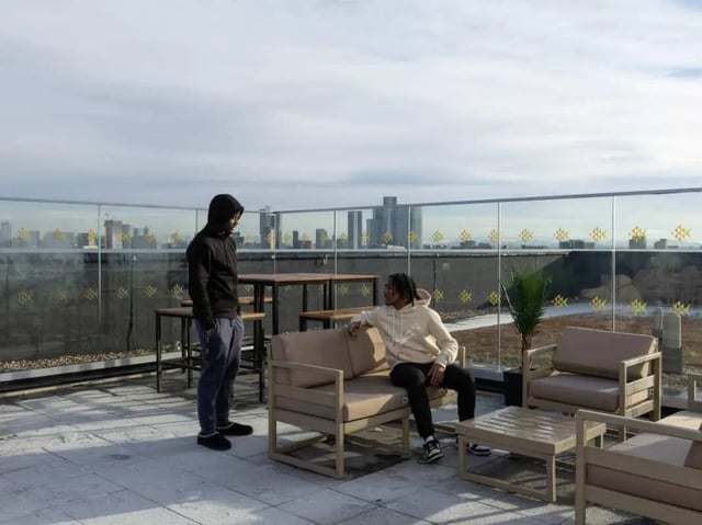 Rooftop lounge area with two people and city view exterior at True Manchester-Salford in Salford Student Accommodation