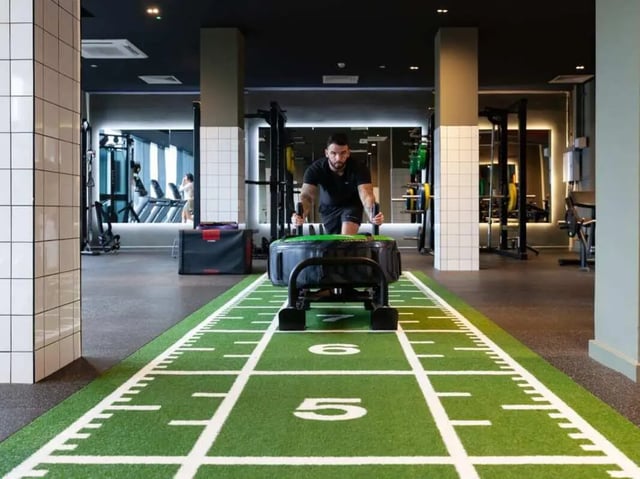 Man pushing tire on turf with gym equipment. Gym. at True Liverpool in Liverpool Student Accommodation