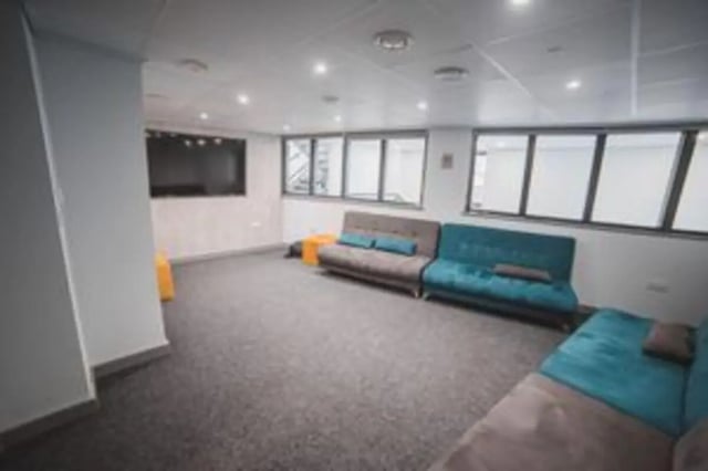 Gray and teal sofas with pillows common area at The Bank Leicester in Leicester Student Accommodation