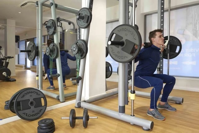 Weight lifter performing squats in gym. Gym area. at The Railyard Cambridge in Cambridge Student Accommodation