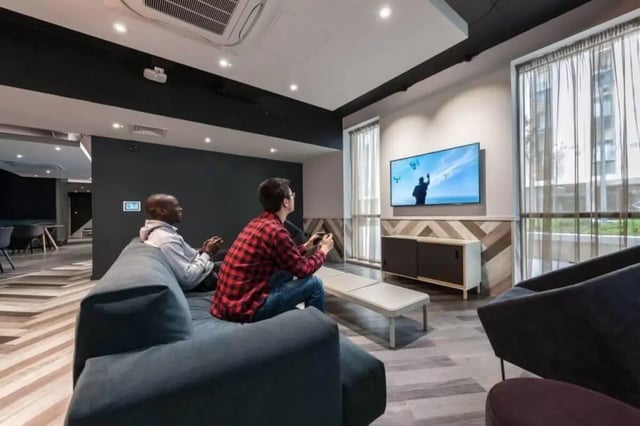 Two men playing video games on couch living room at CitySide in Leeds Student Accommodation