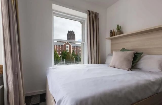 Bed with pillows near window overlooking buildings bedroom at The Arch - Liverpool in Liverpool Student Accommodation