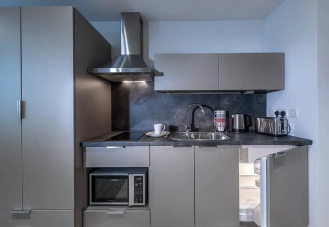 Modern grey kitchen with microwave and fridge Kitchen at Verde in Newcastle Upon Tyne Student Accommodation