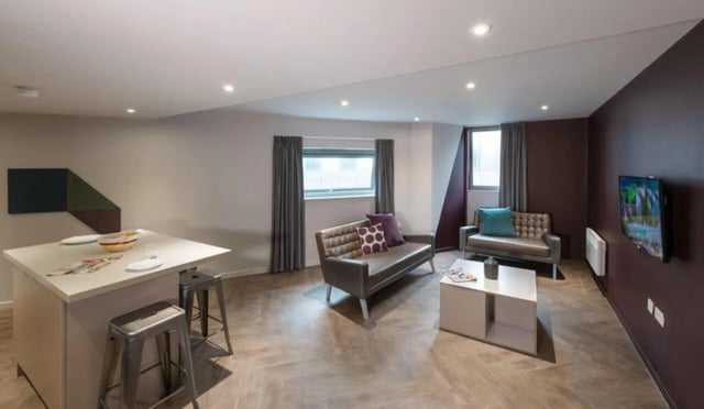 Island kitchen with stools and two sofas living room at Verde in Newcastle Upon Tyne Student Accommodation