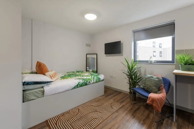 Bed with tropical print pillows and chair bedroom at Marshall Court in Newcastle Upon Tyne Student Accommodation