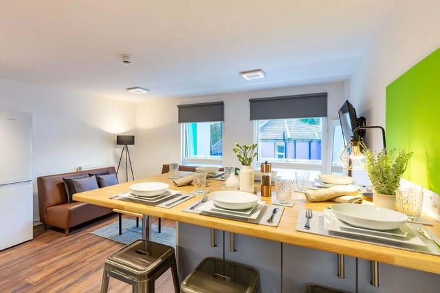 Table with place settings sofa and fridge living room at Newton Court in Newcastle Upon Tyne Student Accommodation