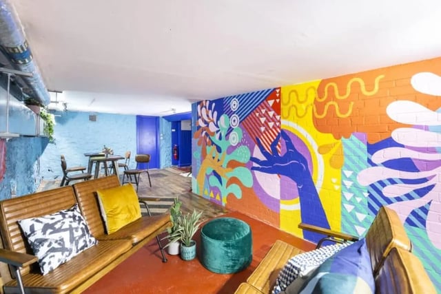 Brown sofas green ottoman colourful mural living room at Tamarillo House in Bristol Student Accommodation