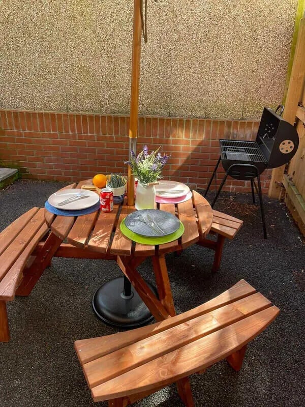 Wooden picnic table with umbrella and grill patio. at Blockyard Apartments in Exeter Student Accommodation