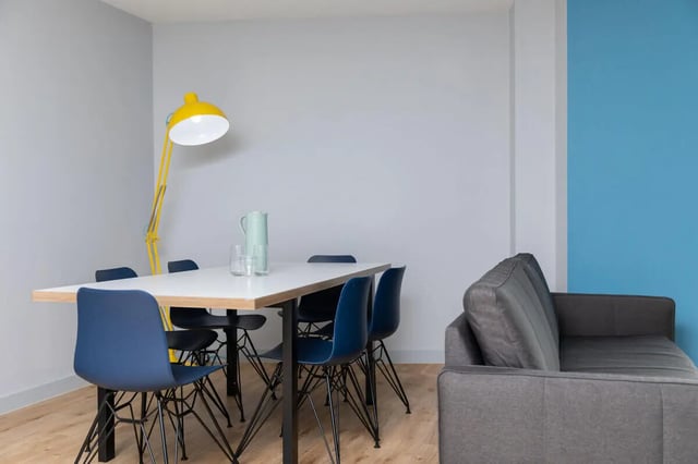Table chairs pitcher glasses lamp sofa living area at West Wing in Cardiff Student Accommodation