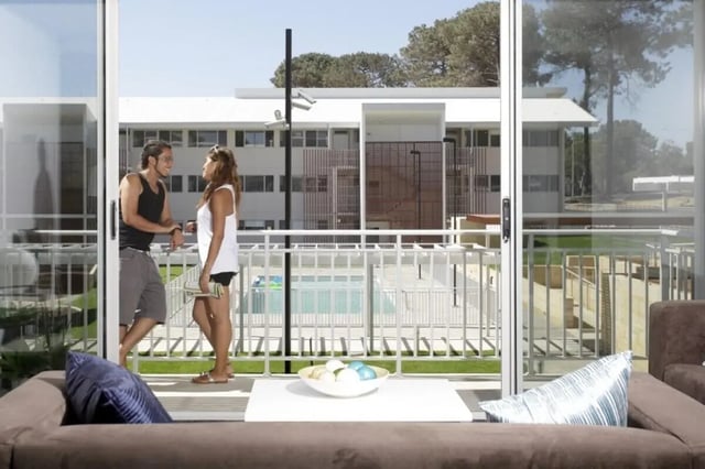 Couple on balcony overlooking pool exterior at Murdoch University Village in Perth Student Accommodation