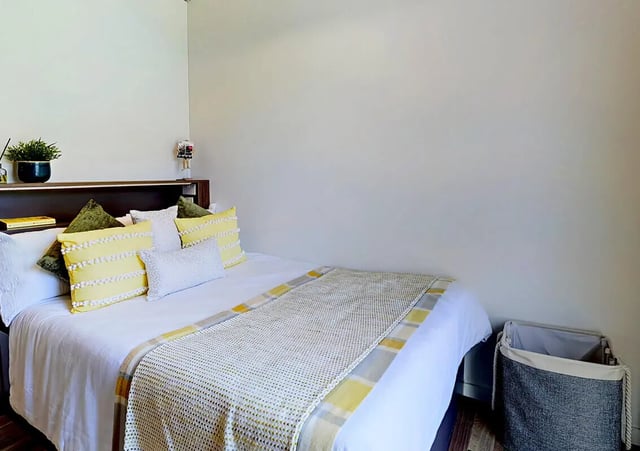 Bed with yellow pillows and throw laundry basket Bedroom at Hox Park in Egham Student Accommodation