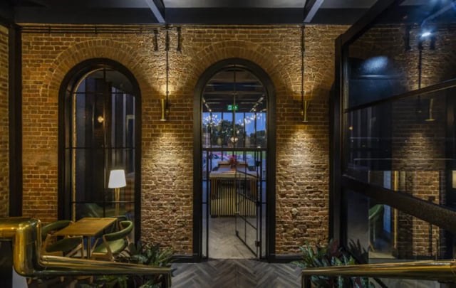 Arched brick doorways showing tables chairs and lighting Lounge at Hox Park in Egham Student Accommodation