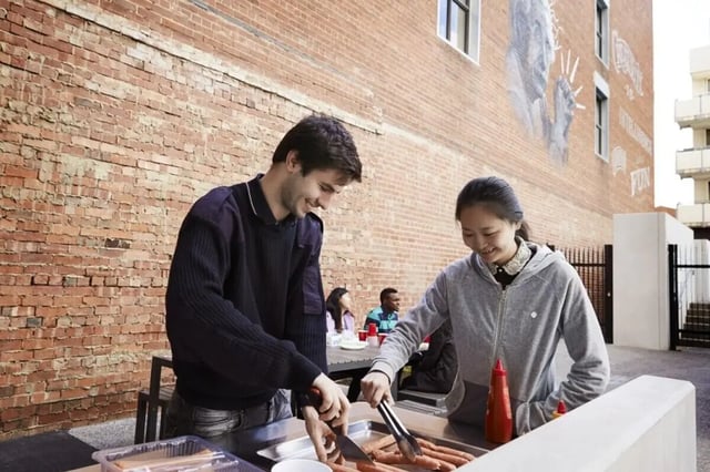 Students grilling hot dogs at an outdoor picnic area exterior at Student Village - University of Melbourne Campus in Melbourne Student Accommodation