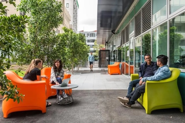 Students sitting on orange and green chairs outdoor patio at Student Village - University of Melbourne Campus in Melbourne Student Accommodation