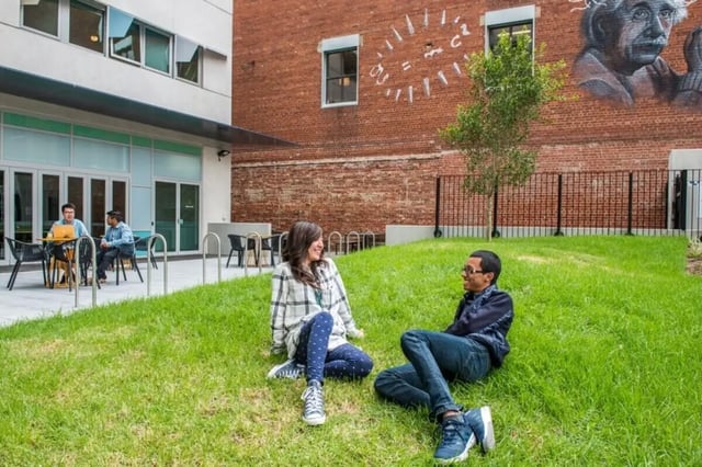 Two students relax on grass with Einstein mural exterior at Student Village - University of Melbourne Campus in Melbourne Student Accommodation