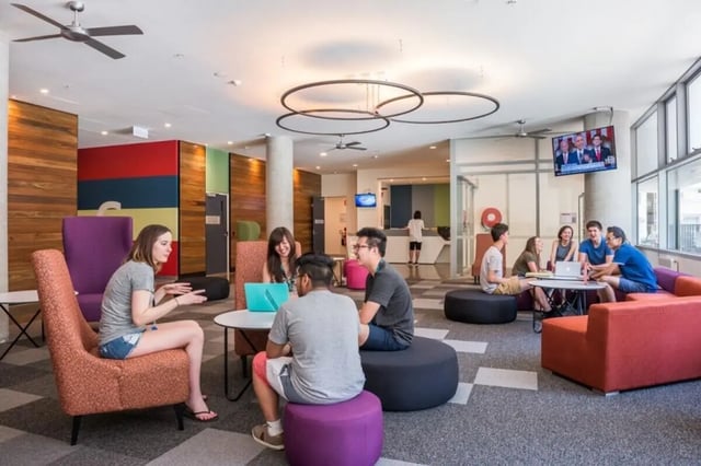 Students sitting around tables and sofas communal area at Student Village - University of Melbourne Campus in Melbourne Student Accommodation
