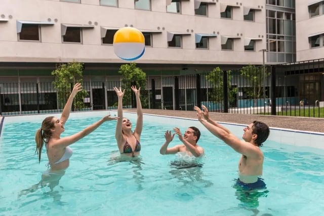 Students play volleyball in an outdoor pool playing area at Student Village - University of Melbourne Campus in Melbourne Student Accommodation