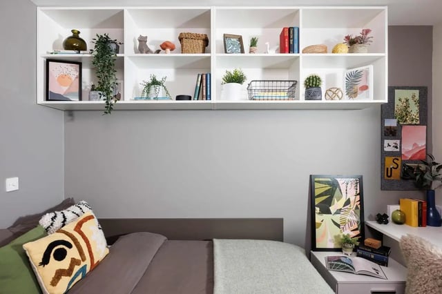 Bed with decorative pillows and wall shelf Bedroom at Exchange Works in Sheffield Student Accommodation