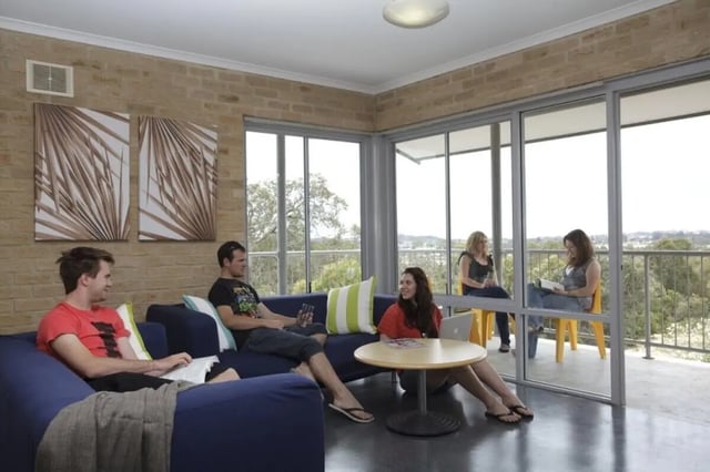 Students on couches by large windows living room at ECU Village Bunbury in Bunbury Student Accommodation