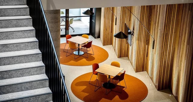 Two tables with chairs on orange rugs communal area at Iglu South Yarra in Melbourne Student Accommodation