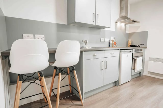 Two white chairs grey cabinets fridge oven kitchen at Market House in Newcastle Upon Tyne Student Accommodation