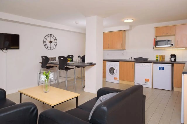 Living area with kitchen appliances dining table and sofas living room at Keiller Court in Dundee Student Accommodation