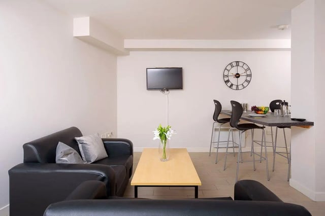 Black couches coffee table bar counter kitchen area at Keiller Court in Dundee Student Accommodation