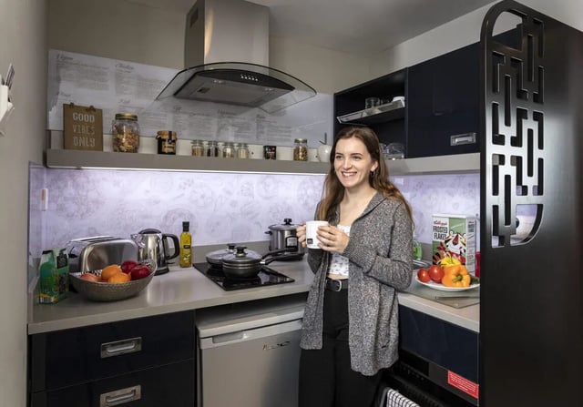 Woman holding mug in modern kitchen with appliances kitchen at Study Inn Walnut Gardens Exeter in Exeter Student Accommodation