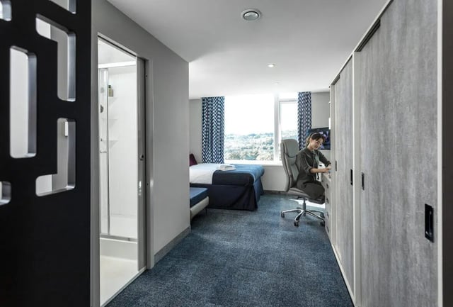 Bed shower desk and person student room at Study Inn Walnut Gardens Exeter in Exeter Student Accommodation