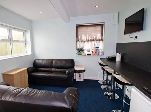 Black sofas bar stools and kitchen counter living room at Radmoor House in Loughborough Student Accommodation