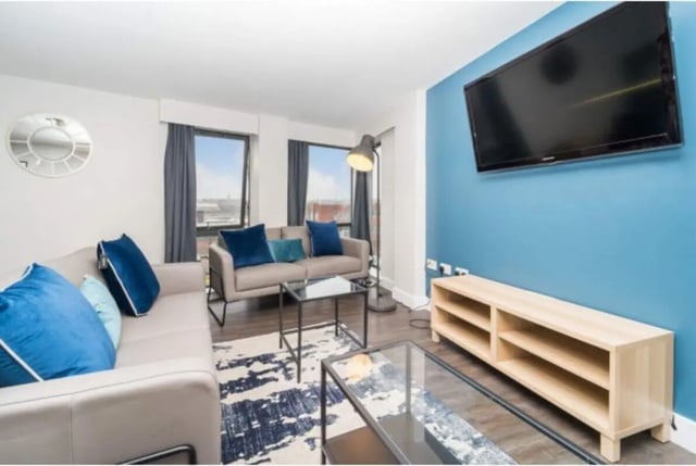 Two sofas with blue pillows coffee tables television living room at The Triangle in Leeds Student Accommodation