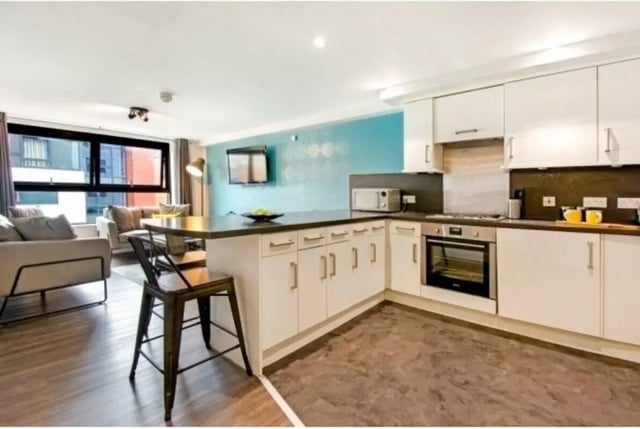 Modern white kitchen with island and living area kitchen at The Triangle in Leeds Student Accommodation