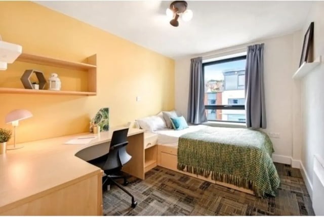 Bed desk lamp chair shelves on yellow wall bedroom at The Triangle in Leeds Student Accommodation