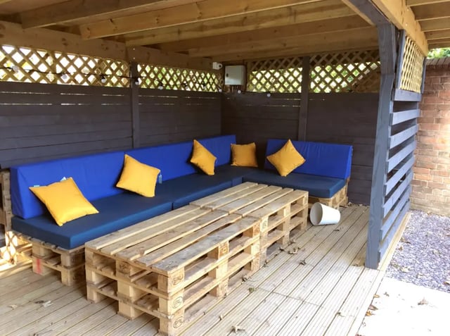 Blue sofa yellow cushions wooden pallet table covered area at Kingfisher Halls in Loughborough Student Accommodation