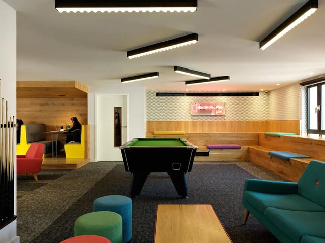 Pool table seating area with neon sign Common area at Student Castle York in York Student Accommodation