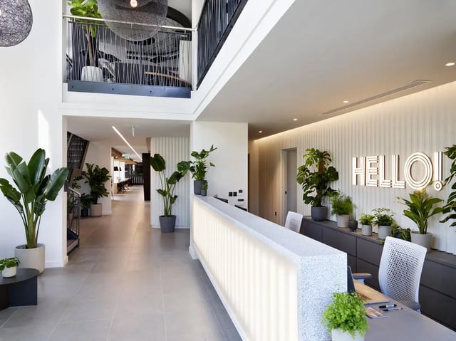 Reception desk with plants and "Hello!" sign lobby at Student Castle Oxford in Oxford Student Accommodation