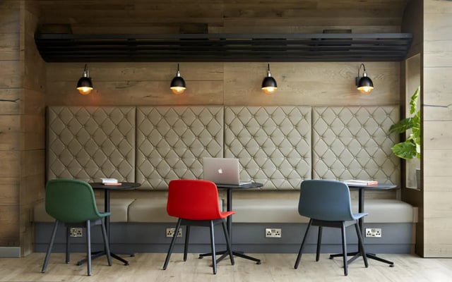 Laptop on table with tufted booth and chairs study area at Student Castle Lincoln in Lincoln Student Accommodation