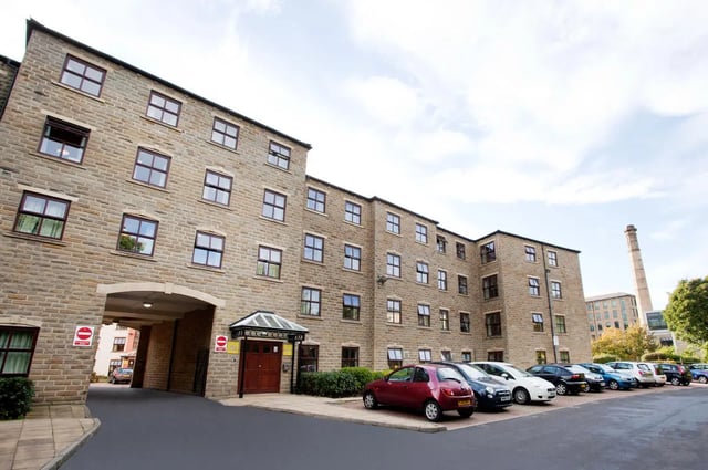 Stone building with cars and arched entryway exterior at Snow Island in Huddersfield Student Accommodation