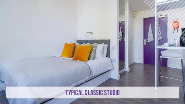 Bed with orange pillows and grey headboard studio at Kensington House in Birmingham Student Accommodation