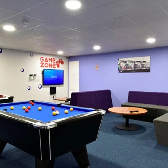 Pool table television purple sofas round table living room at The Courtyard Block A in Huddersfield Student Accommodation