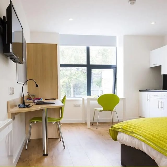 Desk with laptop chairs window kitchen living room at The Courtyard Block C in Huddersfield Student Accommodation