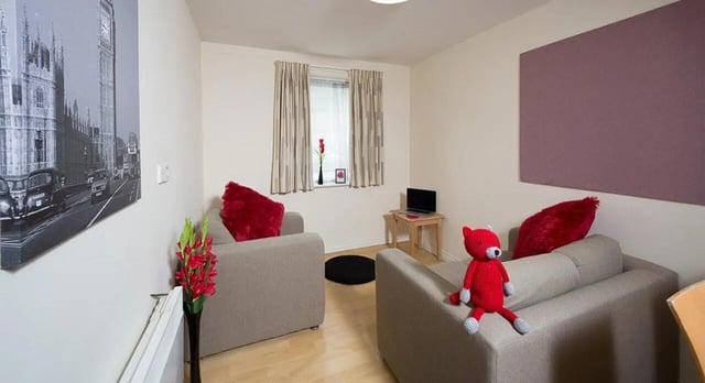 Two sofas red cushions laptop living room at Q3 Apartments in Manchester Student Accommodation