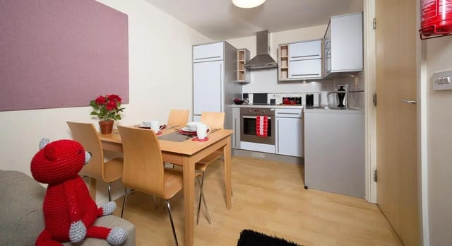 Wooden table chairs kitchen units fire extinguisher kitchen at Q3 Apartments in Manchester Student Accommodation
