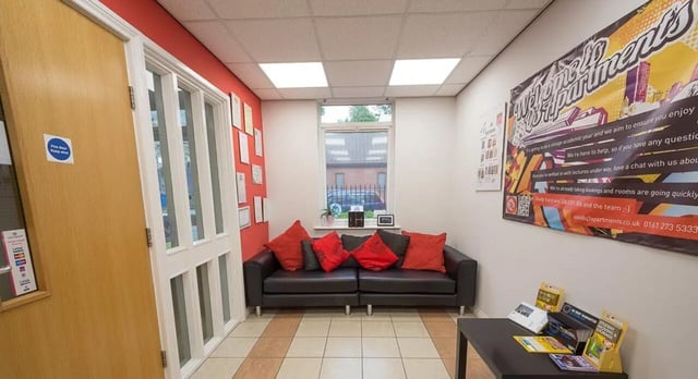 Sofa with red cushions under window reception area at Q3 Apartments in Manchester Student Accommodation