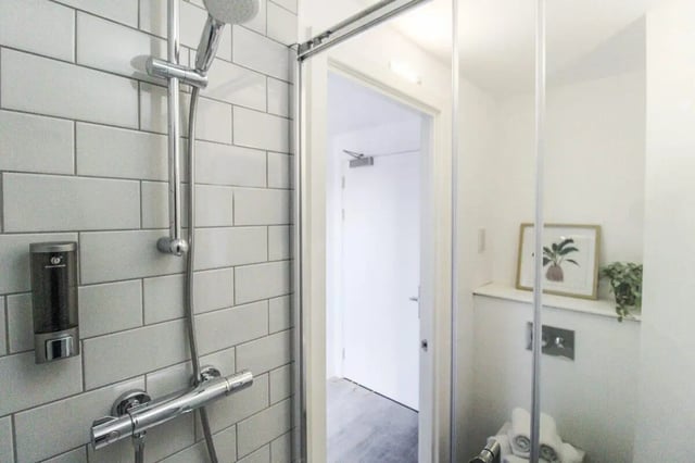 Shower dispenser white tile artwork bathroom at The Nest Leicester in Leicester Student Accommodation