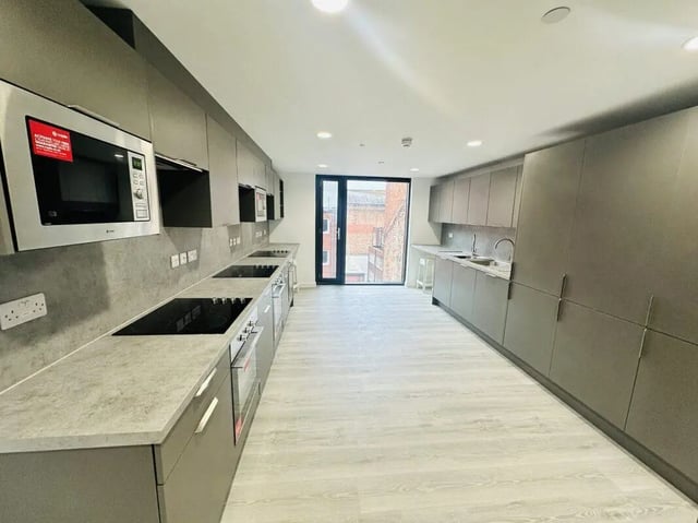 Modern grey kitchen with stovetops ovens and microwave at The Nest Leicester in Leicester Student Accommodation